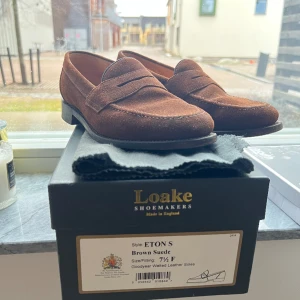 Loake Eton Loafers - Säljer mina loafers som har åldrats med karaktär men fortfarande har mycket att erbjuda. Perfekta för den som uppskattar en touch av vintage i sin stil. Bekväma och slitstarka, dessa loafers är redo att fortsätta följa med dig.  Storlek 42