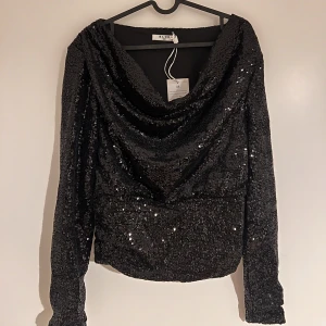 Fin paljettfesttopp - Säljer en helt ny väldigt fin festtopp med paljetter från NA-KD. Har prislappen kvar då jag tyvärr inte hann returnera den. Nypris 449 kr