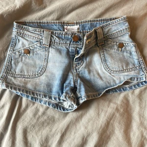 lågmidjade jeans shorts - ett par lite ljusareblå lågmidjade jeans shorts med knappfickor både fram och bak, det står tyvärr ingen storlek på byxan men jag skulle säga att de är typ xs eller 32/34🙏🏻