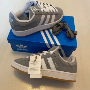 Nya Adidas Campus 00s -storlek 38 - Adidas Originals Campus 00 s j stl 38 Färg: Grå (Grey Three / Cloud White / Cloud White) Ingår både vita och gråa skosnören.  Nya och oanvända. Ligger kvar i kartong.  Köpta i Sverige och inte från itomlands. 100% äkta.  