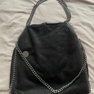Stella lik väska - Säljer en jättefin Stella liknande väska. Den är svart med lite skimmer i sig. Den är väldigt rymlig med många fack, perfekt att ha som skolväska mm 💗