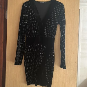 Klänning med glitter - Fin silverglittrig klänning med liten slits ifrån Erica Kvams kollektion x Nelly från några år tillbaka. Bra skick använd ett fåtal gånger. Storlek 36 men passar även 34