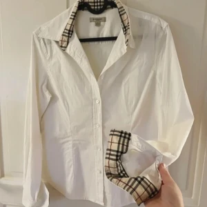 Burberry Skjorta - Äkta Burberry, figursydd damskjorta. I storlek L men en aning mindre i storlek. OBS. Finns inget kvitto 