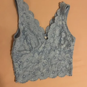 Ljusblå spetslinne - Ett ljusblått spetslinne med blommönster. Linnet har en v-ringad hals och är ärmlös. Det är tillverkat av spetsmaterial och har en tight passform. Skriv gärna om ni har frågor 💕