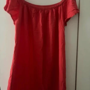 Röd klänning från 151a - En röd klänning från lager 157 med korta ärmar och en elastisk halsringning. Klänningen är enkel och stilren, perfekt för sommarens varma dagar.