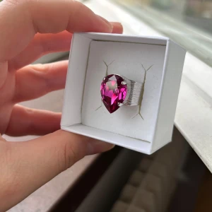 Ny Caroline Svedbom ring - Ny ring från Caroline Svedbom i modellen Classic Drop. Oanvänt, i ny/ utmärkt skick. Stenfärg: Fuchsia/ mörk rosa. Ringen har en öppen baksida som lätt kan justeras. Storlek: 18 x 13 mm, justerbar. Rodiumplätering. Ask medföljer. Nypris 695 kr