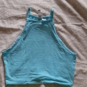 Blå linnetopp från Divided - En blå linnetopp från H&M Divided. Toppen är ärmlös och har en enkel design med rund halsringning. Köpt för 1 år sedan, använd några gånger. Storlek S. 