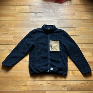 Fat Moose Fleece Jacka - Mörkblå och beige, dragkedja, två fickor längst ner var sida om dragkedjan samt en vid bröstet och två stora inuti, nästan nyskick, large, lite nopprig inuti, ett par spretiga trådar vid dragkedjan. Säljer den eftersom den inte längre är i min stil.