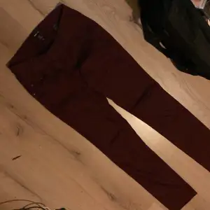 Ett par vinröda byxor från H&M Mama i storlek L. Byxorna har en tight passform och är designade för att vara bekväma under graviditeten.