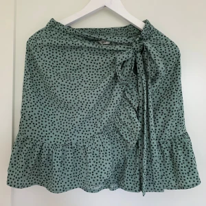 Grön omlottkjol  - Jag säljer en grön kjol med svarta små blommor i storlek S, varan har använts en del men är fortfarande i ett bra skick!