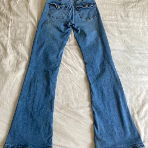 Blå jeans med fickor  - Säljer mina blå jeans med fickor från young gina. Jeansen är använda fåtal gånger och i nyskick. 