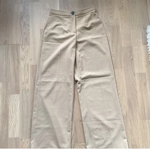 Beiga kostymbyxor - Beiga kostymbyxor som passar någon i storlek xs/34. Vida ben och små i midjan. Högmidjade i modellen. De är även uppsydda så att de passar mig som är 163. Går att sprätta upp så att de blir 5 cm längre om man skulle vilja 🤍