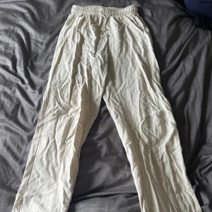 Beige linnebyxor - Ett par beige linnebyxor i storlek xs. Byxorna har en elastisk midja och är tillverkade av linne, vilket gör dem lätta och bekväma att bära.