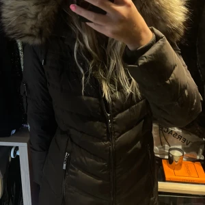 Vinterjacka Bark - Brun vinterjacka från Bark med päls på luvan. Flertalet fickor med dragkedja samt skärp för midjan. Storlek M. Ytterst lite använd.