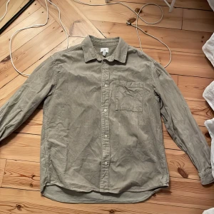 Grön overshirt - Grön/beige tjockare skjorta i Manchester-material. Kan användas som antingen skjorta eller overshirt!! Storlek L men passar mig som annars har M