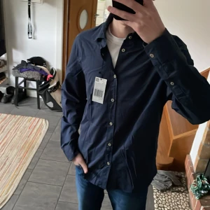 Lätt blå skjorta Mango - Storlek S, kunde inte lämna tillbaka innan 30 dagar, alltså helt ny. Mörkblå lätt sommarskjorta från Mango. Köpt för 500 kr.