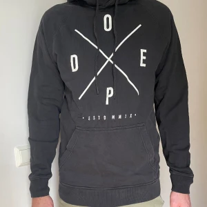 Svart Dope hoodie - Säljer en svart Dope hoodie. Den är ca 2 år gammal, lite använd. Skick 7/10 och den är storlek M.