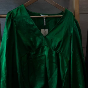 Blus, Object - Festlig satin-blus i härlig grön färg och rosett detaljer vid ärmarna. Den är aldrig använd och har lapparna kvar. Storlek 36 💚