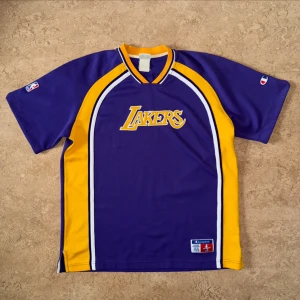 Vintage Champion Lakers tröja - T-shirt i tjockare funktionsmaterial från Champion med embroderade tryck. Från 90-talet. Lite noppig. Storlek XL