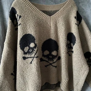 Stickad tröja - Stickad tröja med dödskallar. Använd men fortfarande fin och skön . Den ligger bara i garderoben. Slitage visas på bild.