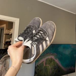 Adidas Gazelle - Säljer mina älskade Adidas Gazelle i den populära mörkgrå färgen! Använda men fortfarande i fint skick! Dem går absolut att rusta upp om man vill med lite tvätt av sulan! Storlek 40 men små i storleken och passar mig som har 39