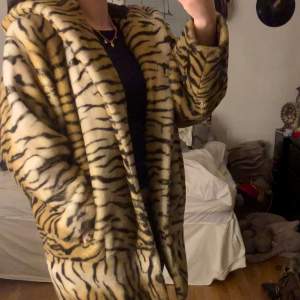 Stor och varm kappa med tiger mönster, stor luva och två rymliga fickor. Den är använd några gånger men inga skador💞