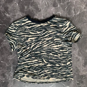 T-shirt - Kort beige T-shirt från HM i zebramönster. Lite urtvättad men annars i jättebra skick.  📷Skriv om ni vill ha fler bilder📷 💸Priset går att diskutera💸