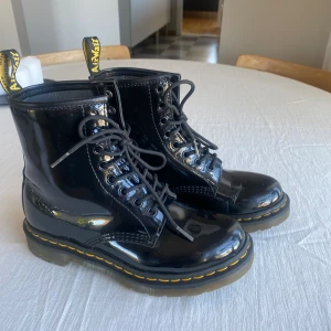 Svarta Dr.Martins boots  - Svarta Dr.Martins boots i högglans. Skorna är i värligt fint skick och är endast använda några få gånger.  Stolek 38. Jag brukar ha storlek 38 i andra skor och skulle därför säga att dem är normala i storleken. 