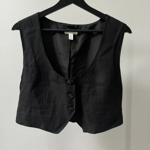 Svart kostymväst - Svart kostymväst från H&M i linne-blandning (linne, polyester och viskos). Sitter oversized. Använd 2 gånger.