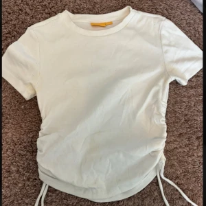 Vit t-shirt - Fin t-shirt som är knappt använd! Den har snören på sidan som man kan justera.