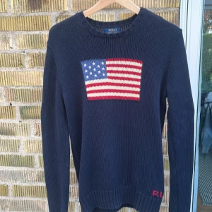 Stickad tröja - Säljer denna marinblåa klassiska stickade Ralph Lauren tröja då den ej kommer till användning. Den är i använt skick men inget som direkt påverkar utseendet, men kan vara större än vad den är från fabrik. Skulle säga att den nu är oversize S.