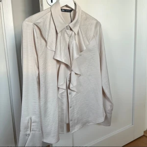 Oanvänd Blus från ZARA - Supersnygg blus från ZARA i storlek M. Snygga detaljer med klockärmar samt de snygga detaljerna med knappar på armarna och längst upp. Snygg beige färg. Aldrig använd, lappen sitter kvar på blusen. 