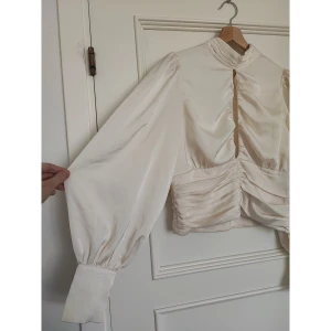 Cremefärgad satinblus  - Superfin satinblus från Gina Tricot med markerad midja, hög krage och cutout, använd en gång så jättefint skick!