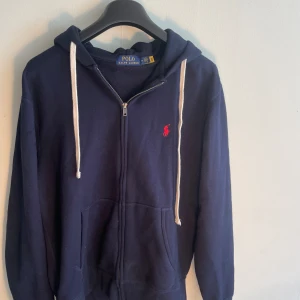 Ralph Lauren-Zip Tröja - Tjena! Säljer nu min mörkblå ziptröja med luva från ralph lauren. Nypris på denna ligger på cirka 1250 och tröjan är lite dammig då den mest legat i garderoben annars inga defekter.