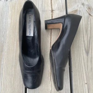 Svarta italienska läderklackar - Svarta klackar med en platt tå och en 5cm klack. Skorna är av läder och gjorda i italien Slitningar i klacken, annars bra skick. Märket är Laura Mannini. Storlek 36