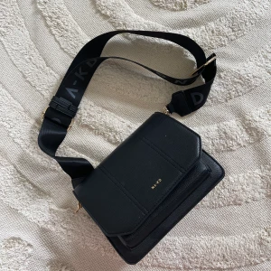 Nakd väska  - Använd. Spännet har gått av som bandet satt i så den sitter i dragkedjan på ena sidan (vilket gör att man inte kan stänga dragkedjan på insidan. Förövrigt varit en favorit.