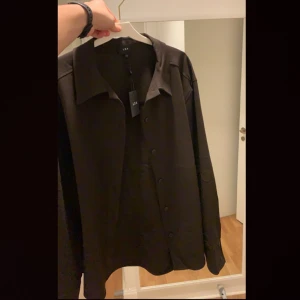 Tunn overshirt i mörkbrunt från LXA - Säljer min overshirt från LXA i storlek M i en väldigt mörkbrun färg. Funkar bra som en vanlig overshirt eller en oversized ”boyfriend shirt”. Säljs pga blivit för liten för mig i storleken numera. Fortfarande i nyskick!