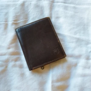 Brun plånbok  - Brun plånbok med massa fack för kort sedlar och mynt. Mått :0x12,5x1 cm när den är ihopvikt. Tror äkta läder  