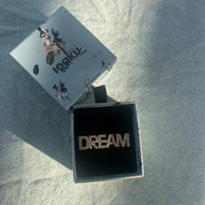 Statement sparkle ring - Ioaku statement ring i guld med motivet ”dream”. Säljer pågrund av dubbletter i present. Den är justerbar i storleken och aldrig använd, älskar den💗