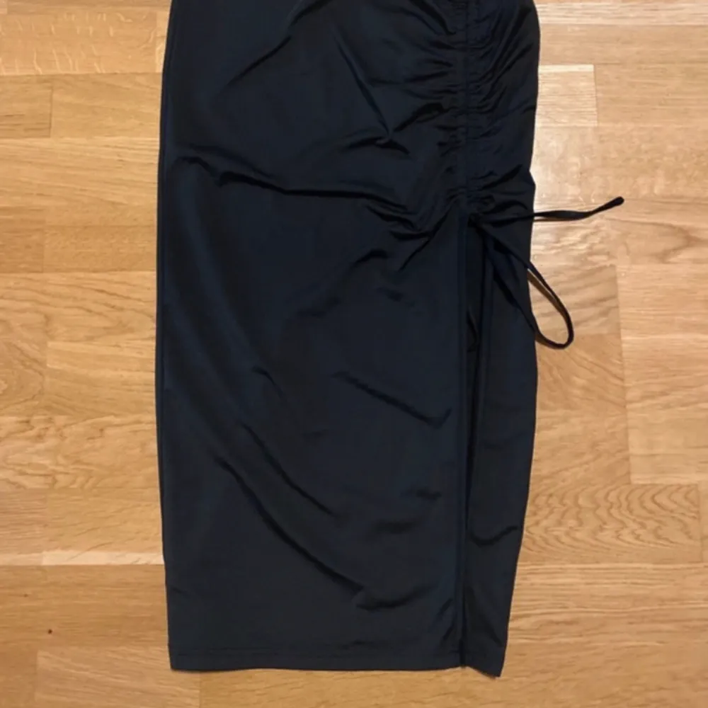En svart långkjol med detaljer/slits på sidan.. Kjolar.