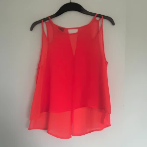 Topp - Säljer en genomskinlig och helt oanvänd topp. Den har en öppen rygg som går lite v ringat. Jätte fin modell vid axlarna. Har en jätte fin neon rosa färg. Men på bilderna ser den röd ut fast den inte är det.  Det går alltid att få fler bilder. 