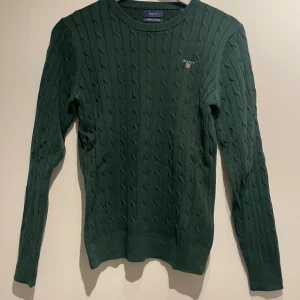 Mörkgrön kabelstickad tröja - Mörkgrön kabelstickad tröja från Gant, bra skick, storlek M.