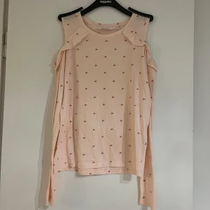 Tröja  - En fin blus/törja till sommaren men den funkar även på våren. Den är Lång ärmad med ett hål vid axeln där det även finns en fin volang. Söta blommor på och en mysig sommar färg. Helt oanvänd 