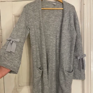 Kofta - Kofta med gråa rosetter. Väldigt varmt material och skön kofta. Barn storlek men passar s/m💞