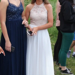 Balklänning - Vit beige balklänning med gulddetaljer+ spets.  Öppen rygg, dragkedja i kanten. Köpt i London på David’s Bridal.  Den går till fötterna på mig som var 170cm i klackar. Står i storlek UK 5 (= EU 38) men  tror mer på strl 36/S.  Endast använd en gång!