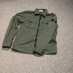 Stone island overshirt - Säljer denna overshirt/jacka då den blivit för liten för mig. Storleken är i junior, passar som xs. Köpt för 2500 på Nk. Storlek 12.