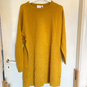 Stickad klänning - Kort stickad klänning. Aldrig använd. Färgen är lite mörkare gul, bilden visar färgen bra. Jag är ca 170cm och den går till mitten av låren på mig. 