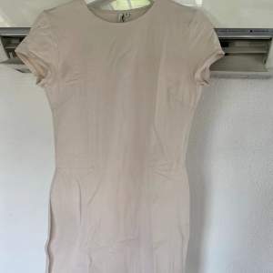 Beige klänning från NLY Trend (Nelly.com) med t-shirt ärmar, stretchigt material, rundad halsring och kort modell. Använd fåtal gånger, väldigt fint skick.