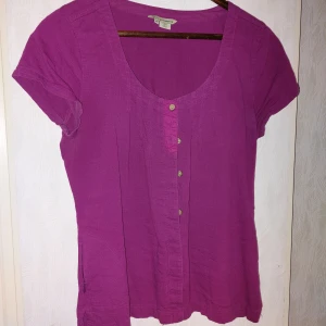 Bomullsblus med ficka - Hallonröd blus i ekologisk bomull. Sidoficka i höger med blixtlås. 