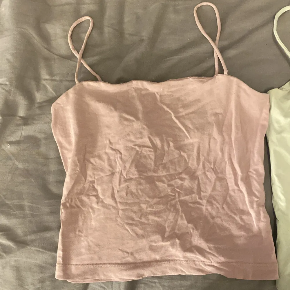 Ett ljusgrönt och ett ljus lila/rosa linne ifrån Ginatricot. Köp båda för 60kr eller en för 35. Toppar.
